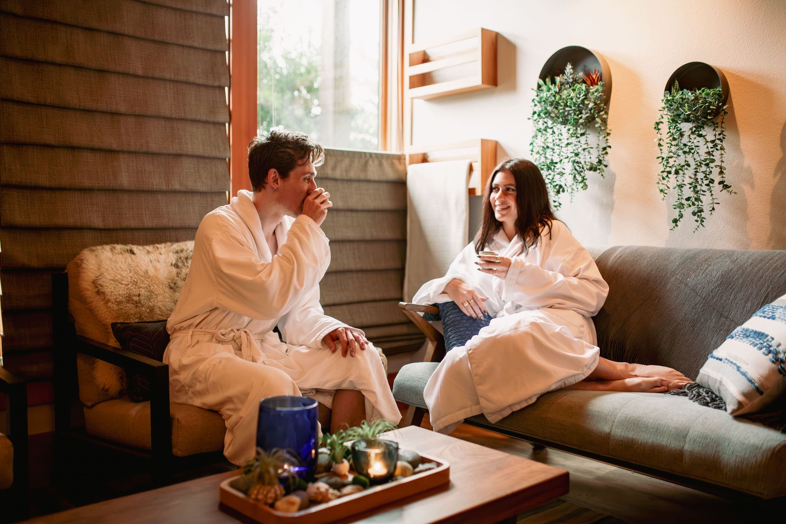 Two people in robes sitting and drinking some tea in the spa lounge area