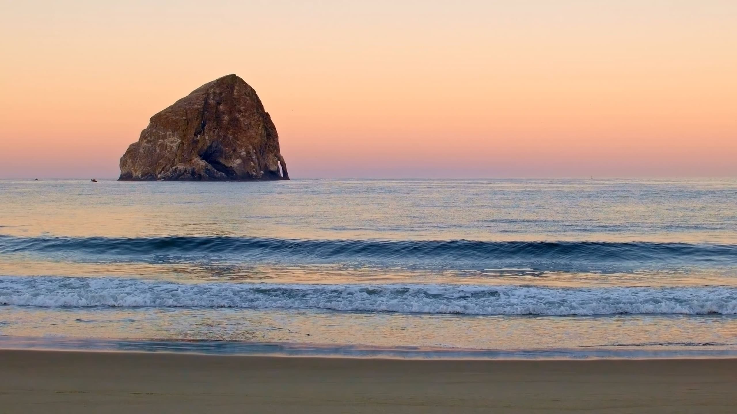The ocean at cape Kiwanda at sunset with a pink sky sprawling over the ocean water