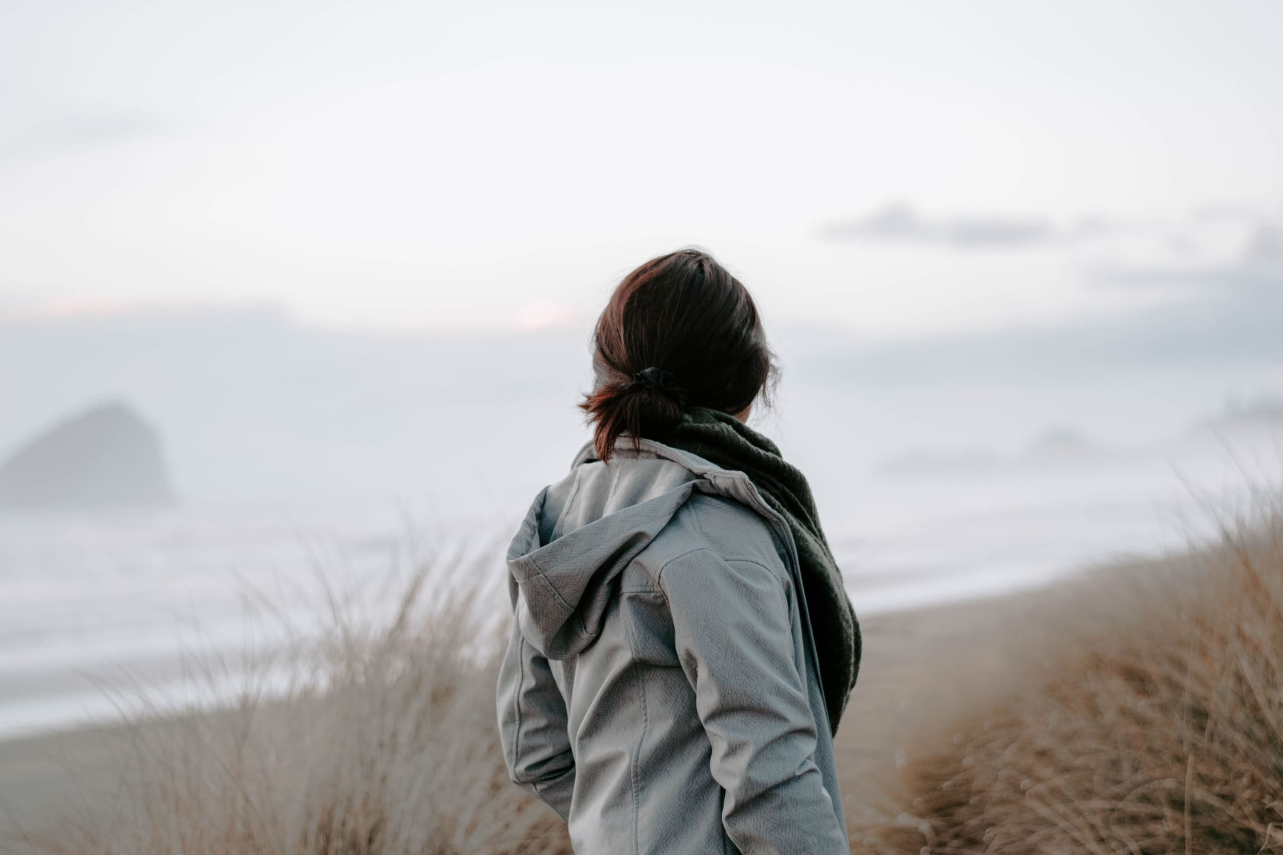 A woman looking at the beach from a trail near Harts Camp