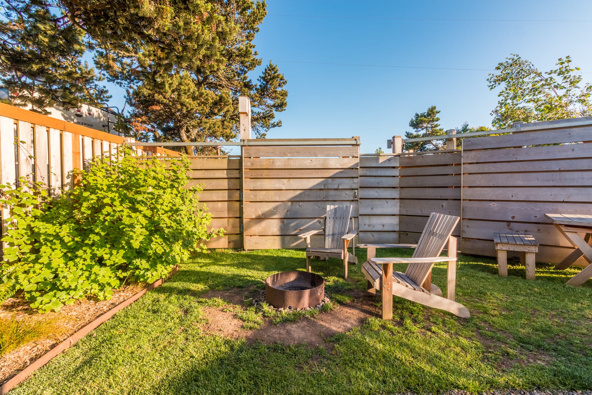 A grassy fire pit area outside a standard airstream at Harts camp