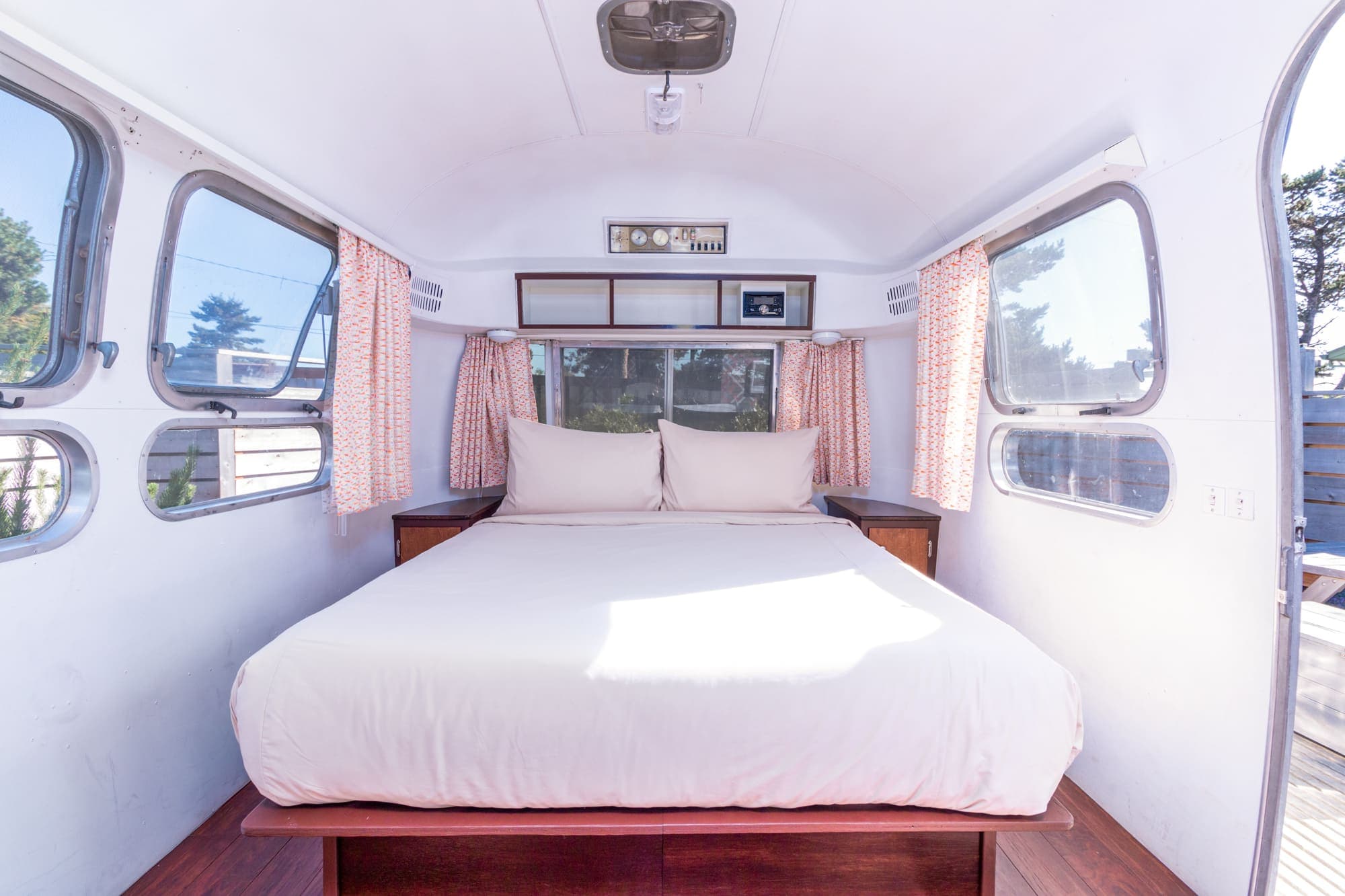 The bedroom with a double bed and windows on both sides in a vintage airstream at Harts Camp