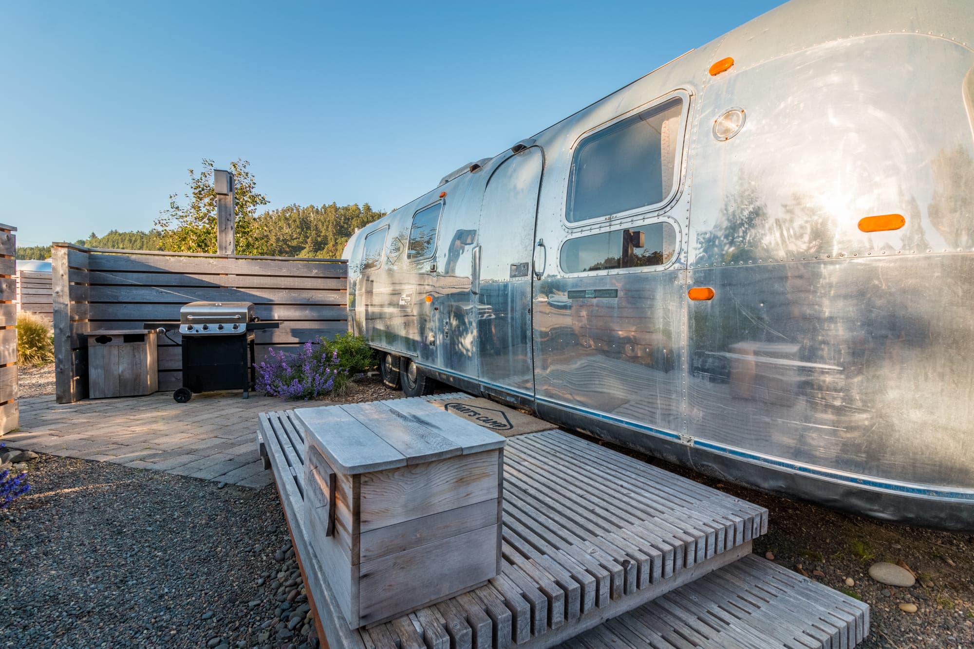 The exterior of a vintage airstream with a BBQ area at Harts Camp