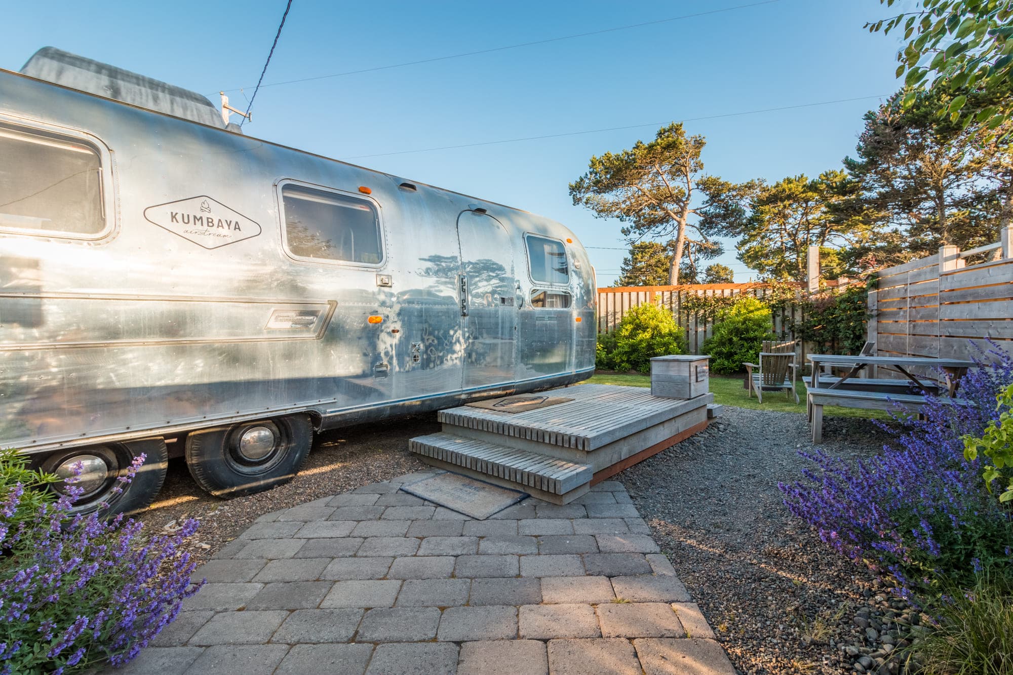 The exterior of a vintage airstream with a picnic table and fore pit