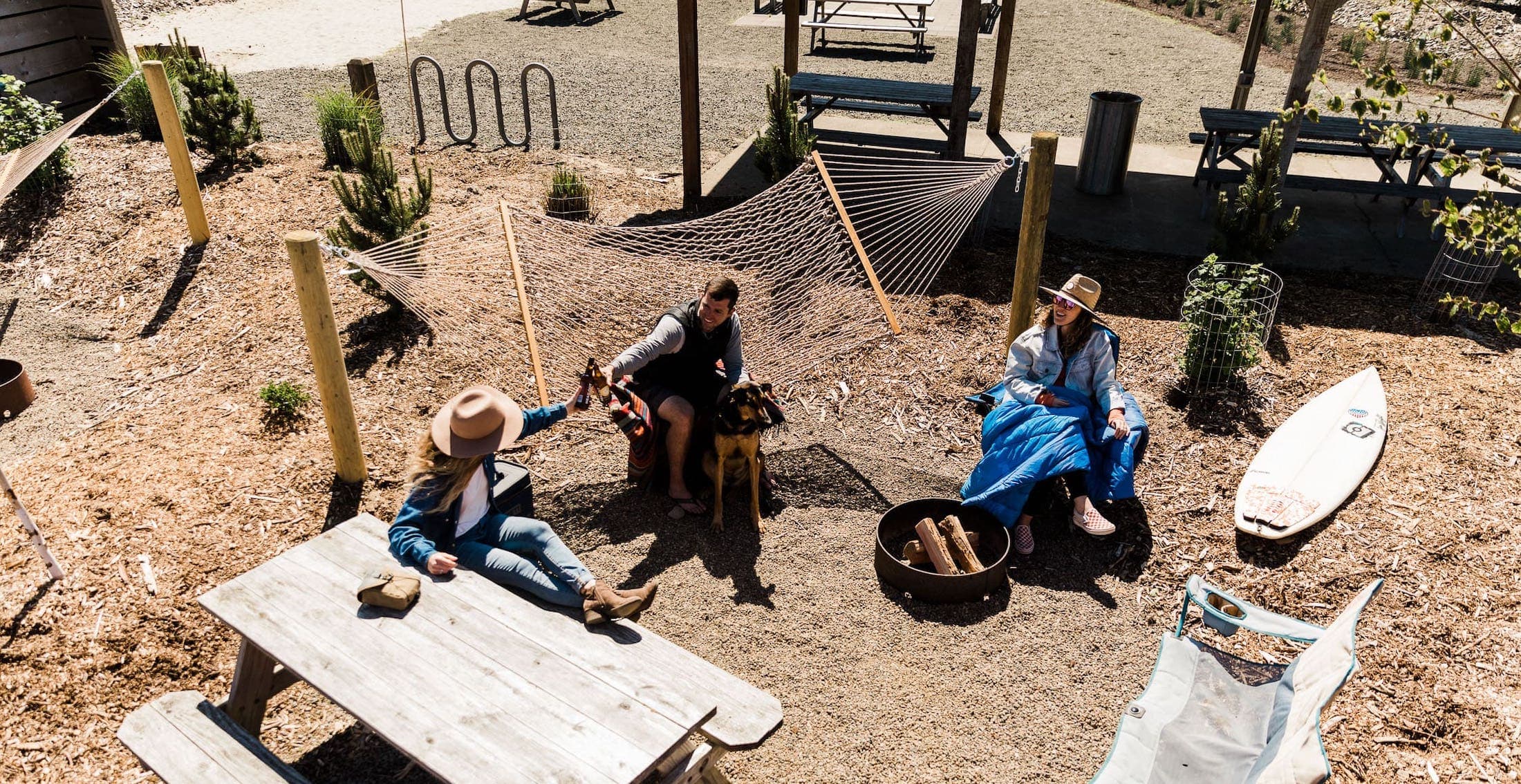 3 people and a dog lounging around a fire pit at Hart's Camp