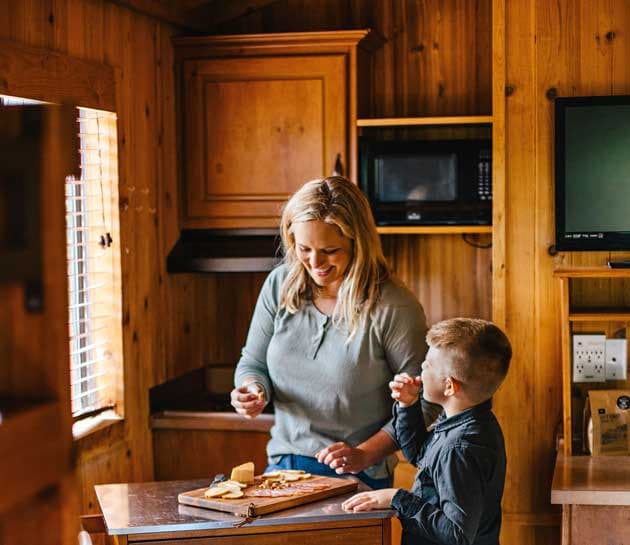 A mother and son eating from a charcuterie board in a cabin at Harts Camp