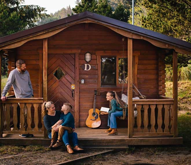 A family having fun on the front porch of a cabin at Harts Camp