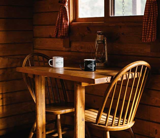 A close up of a table with two coffee cups inside a cabin at Harts Camp