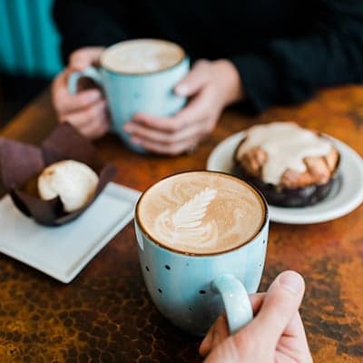Two people sitting and having cappuccino and deserts at Stimulus Coffee