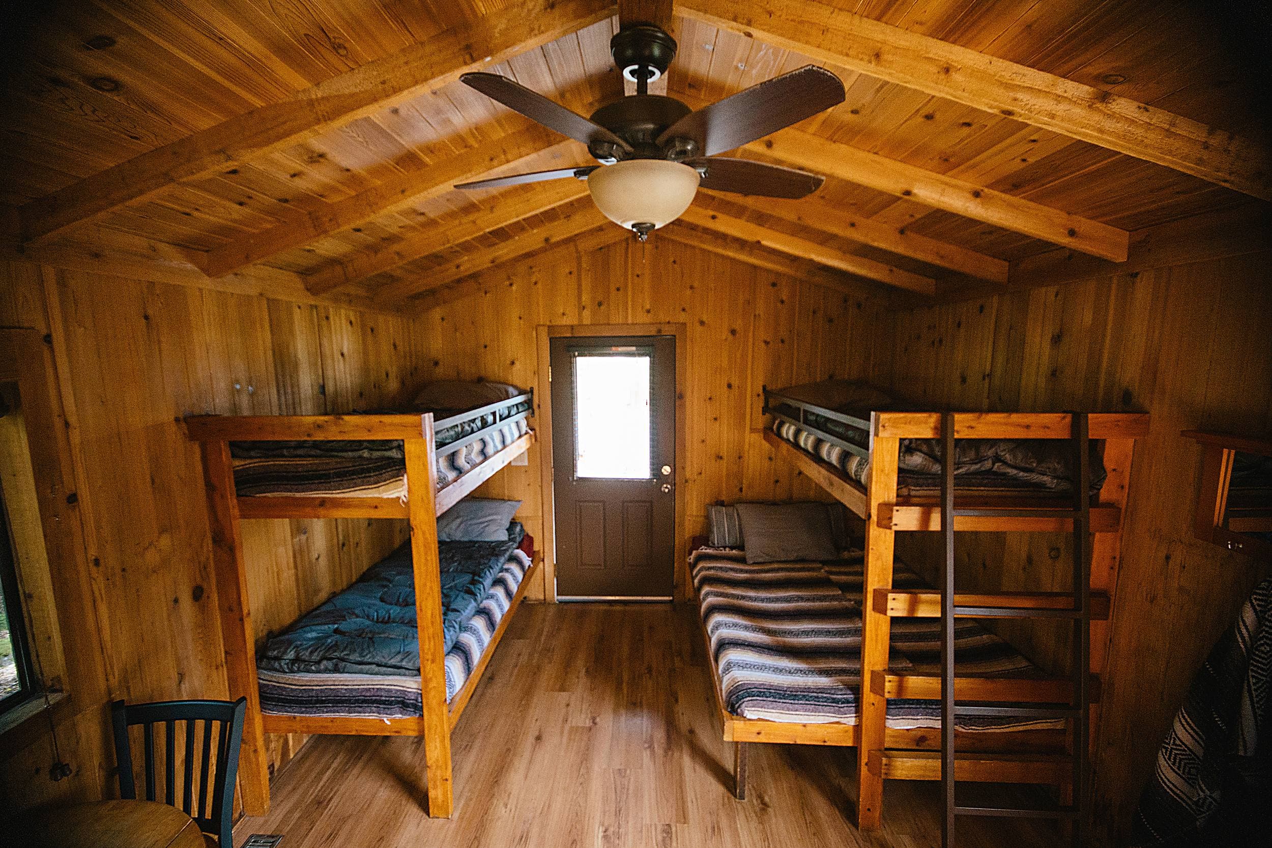 Interior of a cozy wood-paneled camping cabin with two sets of bunk beds at The Inn at Hart's Camp, family-friendly lodging near Cape Kiwanda in Pacific City on the Oregon Coast.