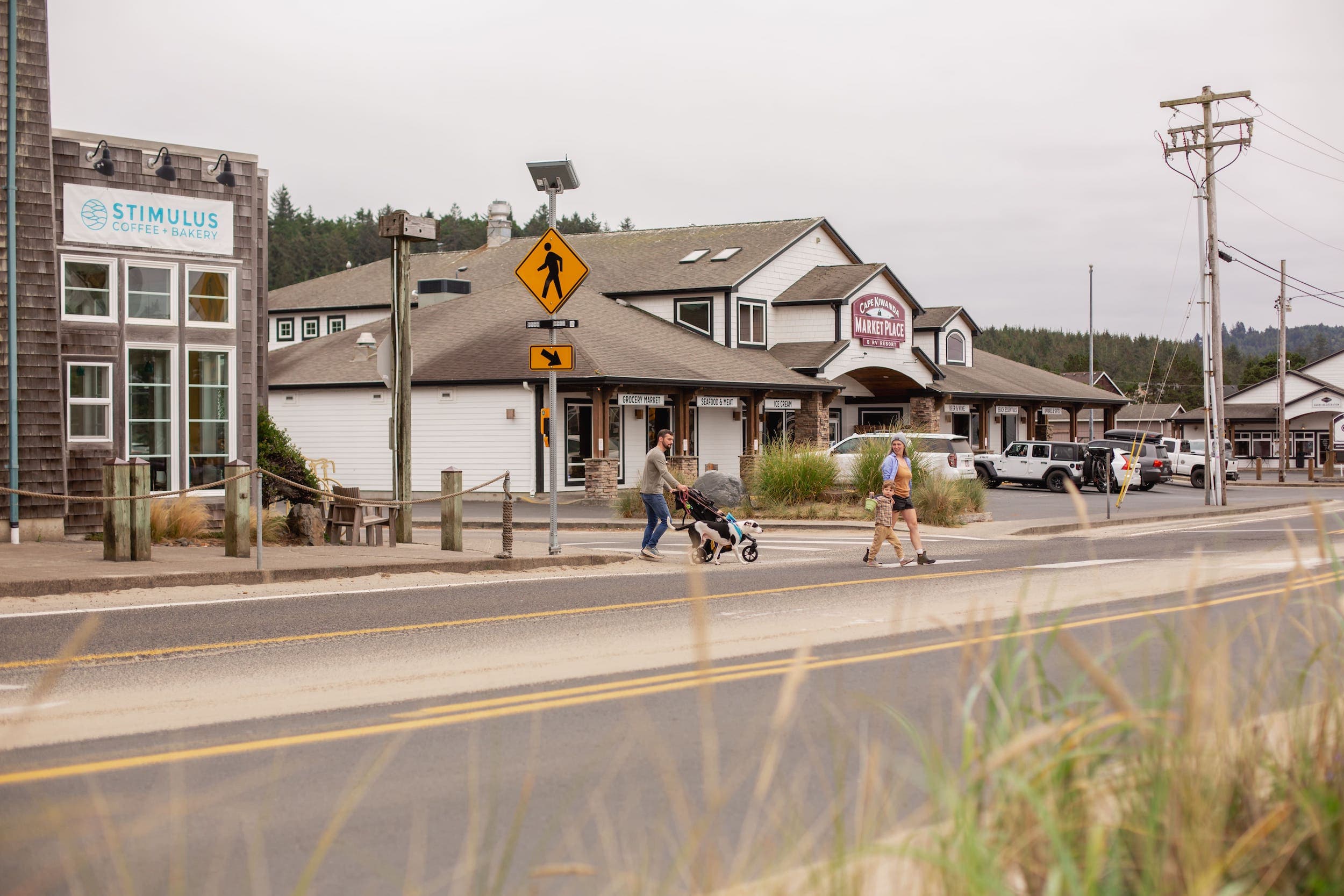 A family of 4 walking across the road outside Stimulus Coffee + Bakery and the Cape Kiwanda Marketplace