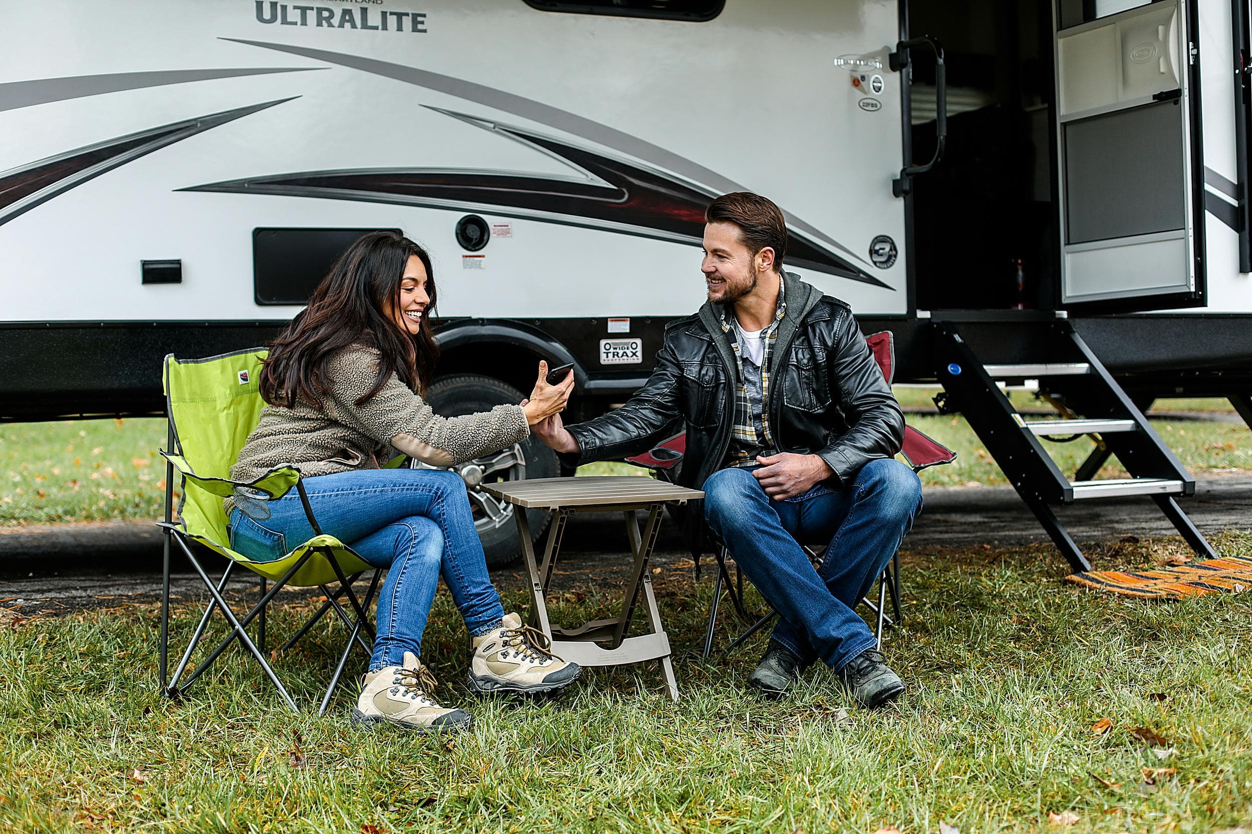 Couple relaxing in camp chairs outside their travel trailer at The Inn at Hart's Camp RV resort in Pacific City, Oregon Coast.