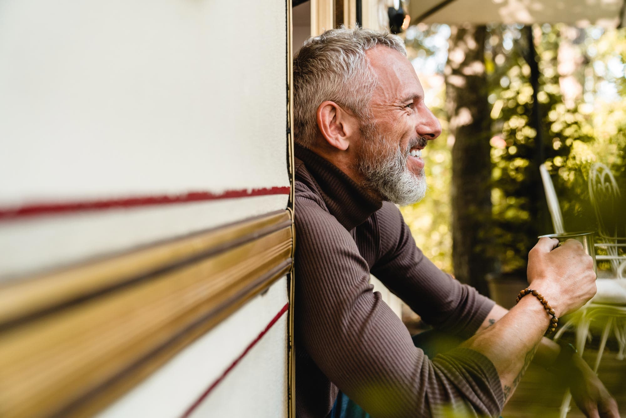 man sitting in rv door drinking coffee