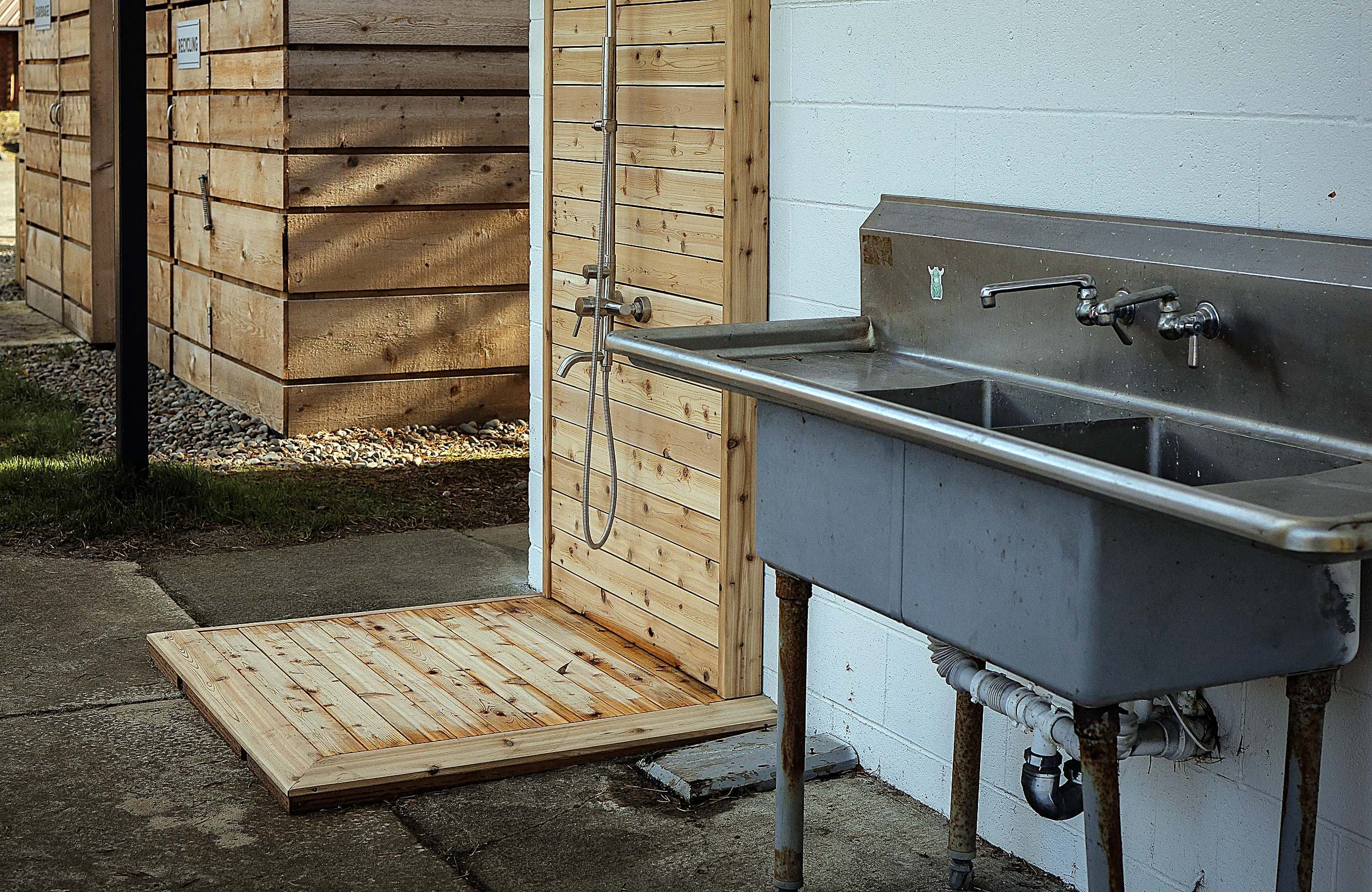 Cedar-paneled outdoor rinse shower and wash sink for sandy paws and gear at The Inn at Hart's Camp, a pet-friendly glamping resort on the Oregon Coast