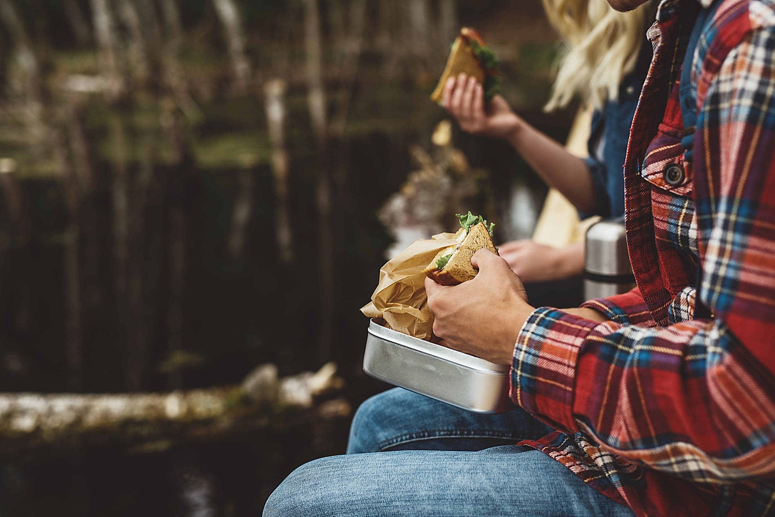 Couple sharing packed sandwiches on a creekside hike near Cape Kiwanda, The Inn at Hart's Camp in Pacific City, Oregon