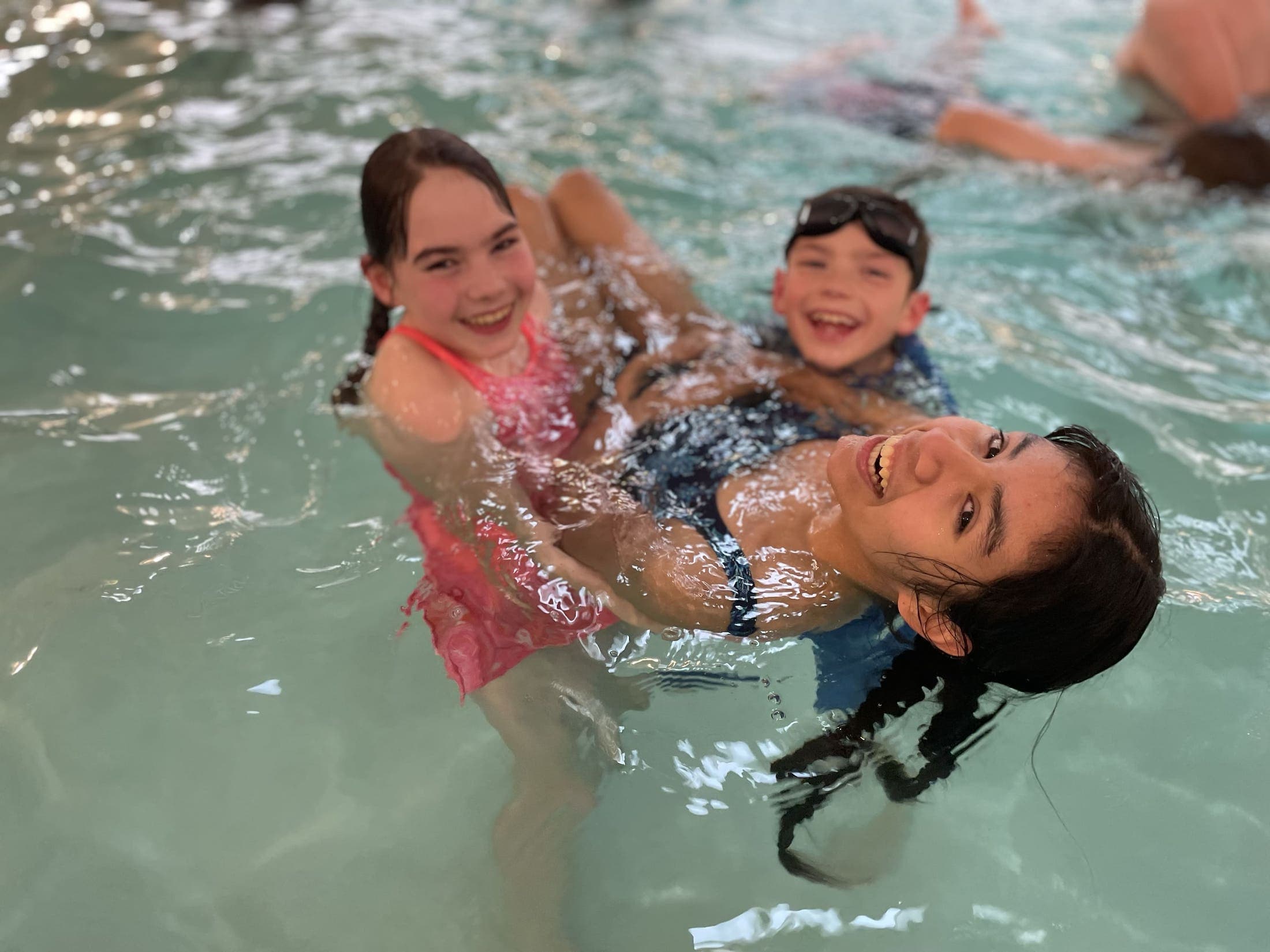 3 children swimming in the swimming in the indoor swimming pool at Hart's Camp
