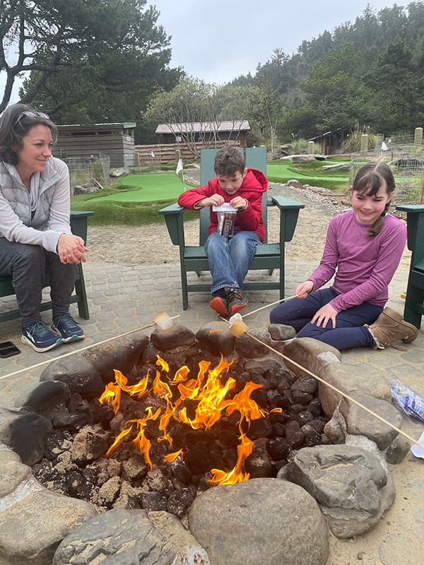 A family sitting beside a fire pit making Smores at Hart's Camp