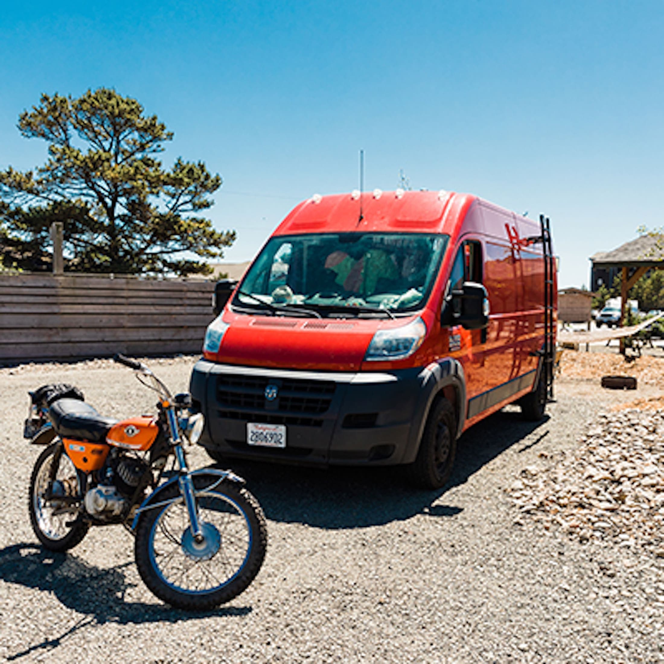 A red van and dirt bike park at a van site at Hart's Camp, Pacific City, OR.