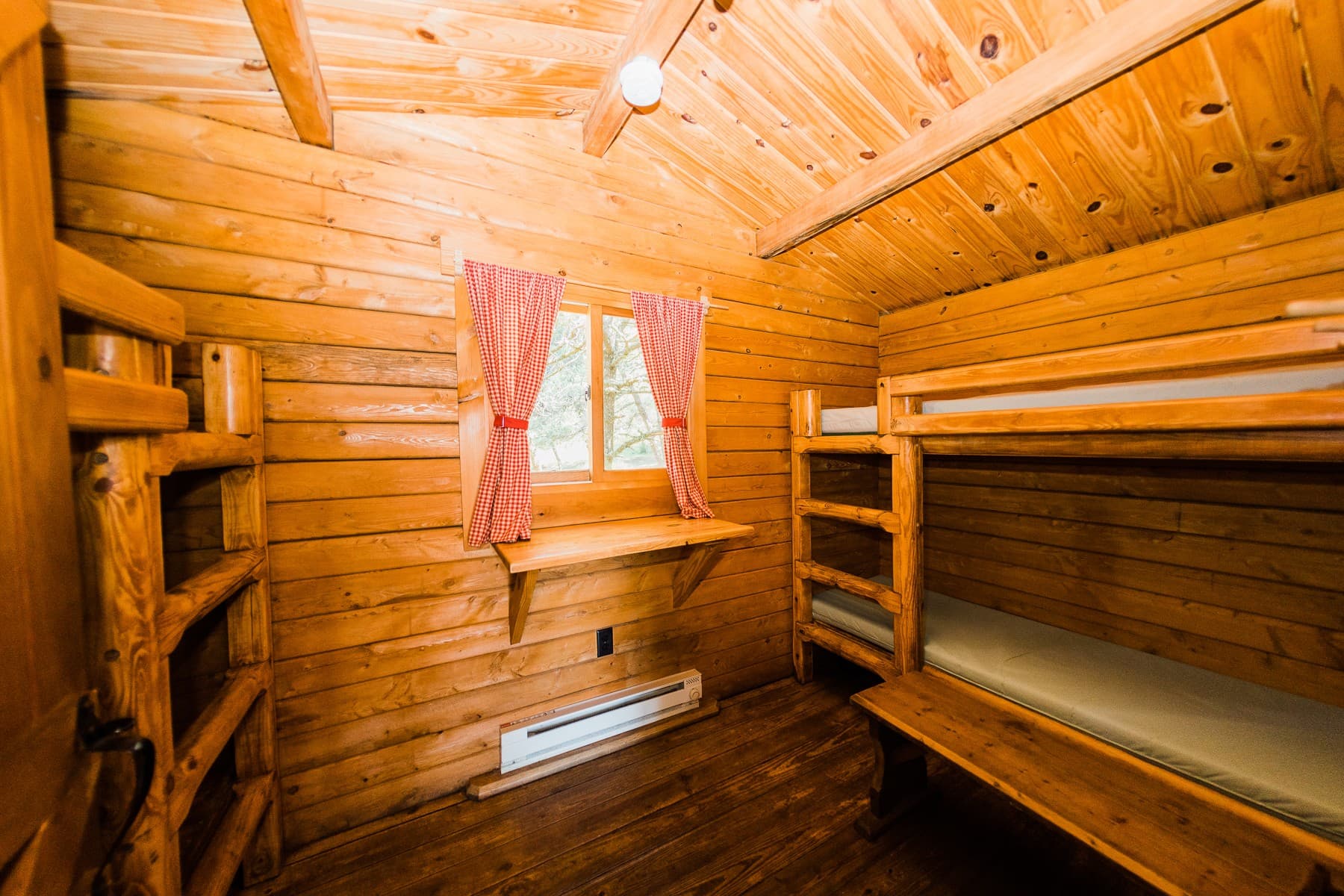 Bunk bed cabin with window shelf and red checked curtains at pet-friendly Hart's Camp in Pacific City, Oregon
