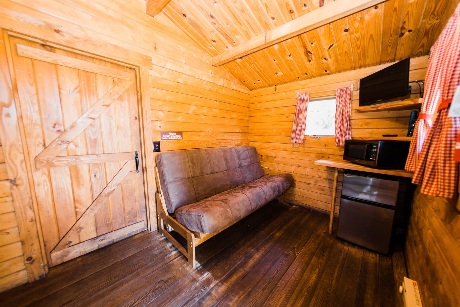 Camping cabin sitting area with futon, mini fridge and microwave at The Inn at Hart's Camp on the Oregon Coast