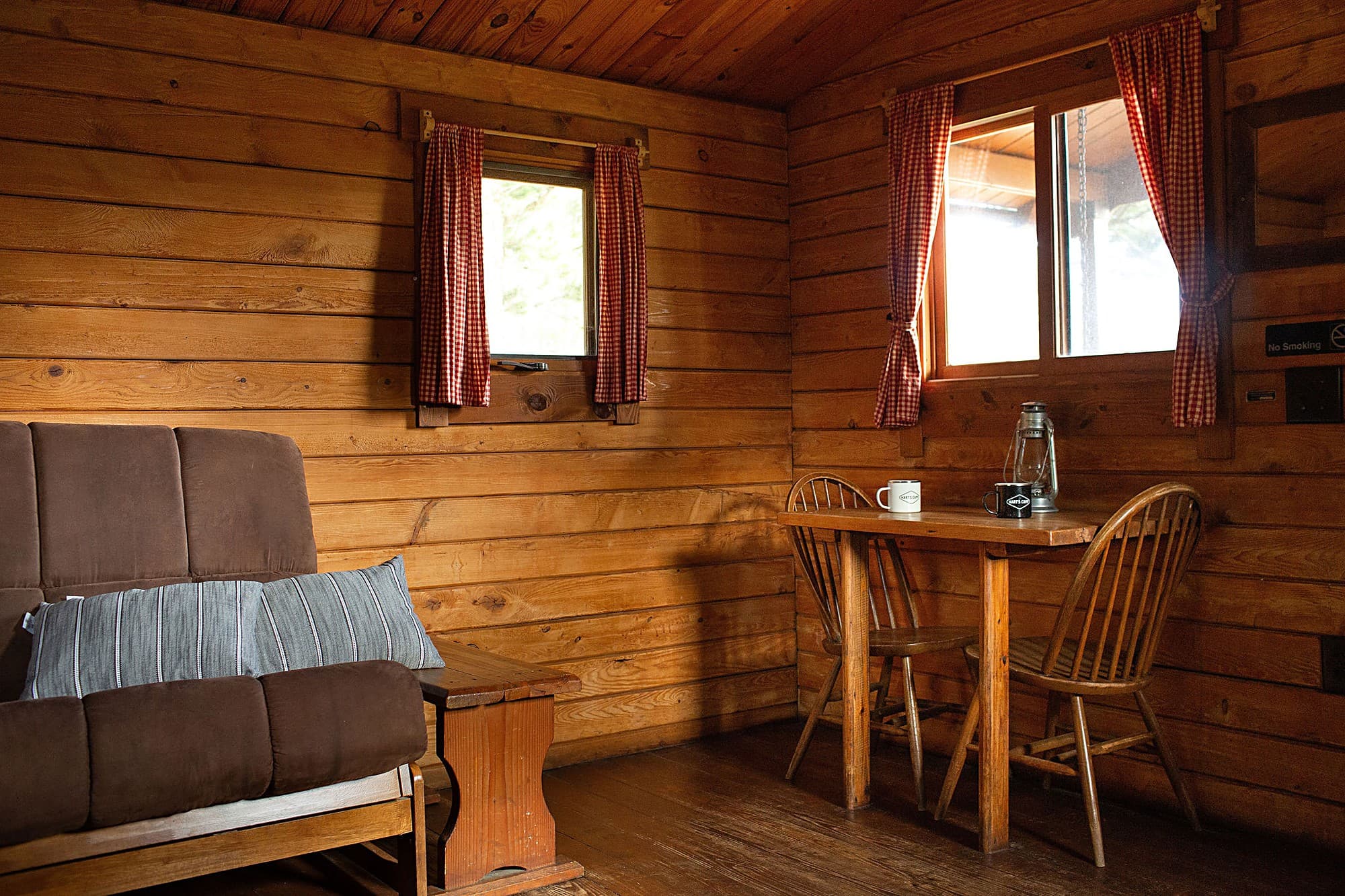 Cozy cabin living area with a futon, dining table and Hart's Camp mugs at the Pacific City, Oregon glamping and RV resort