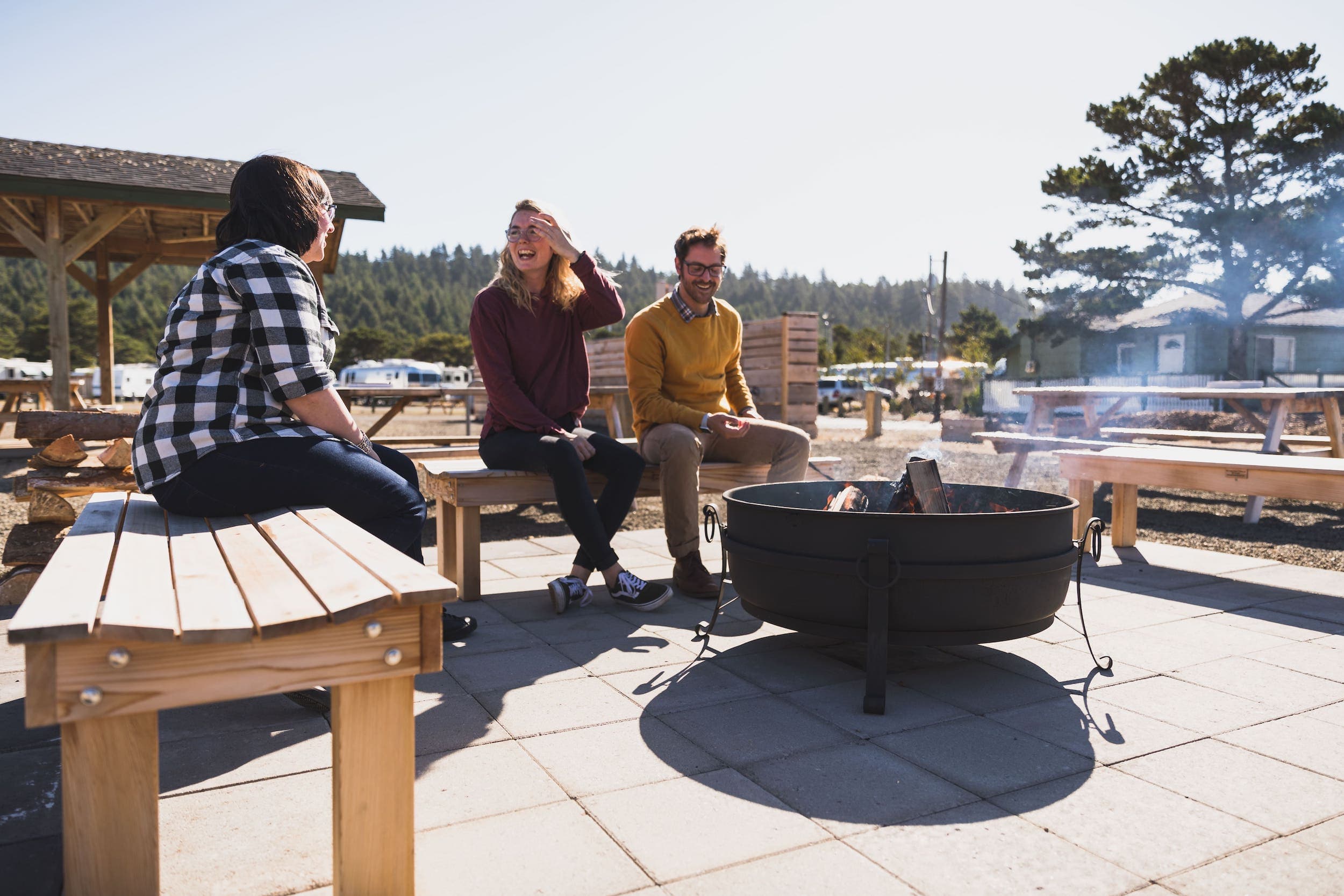 A group of people sitting beside a contained fire pit at Harts Camp