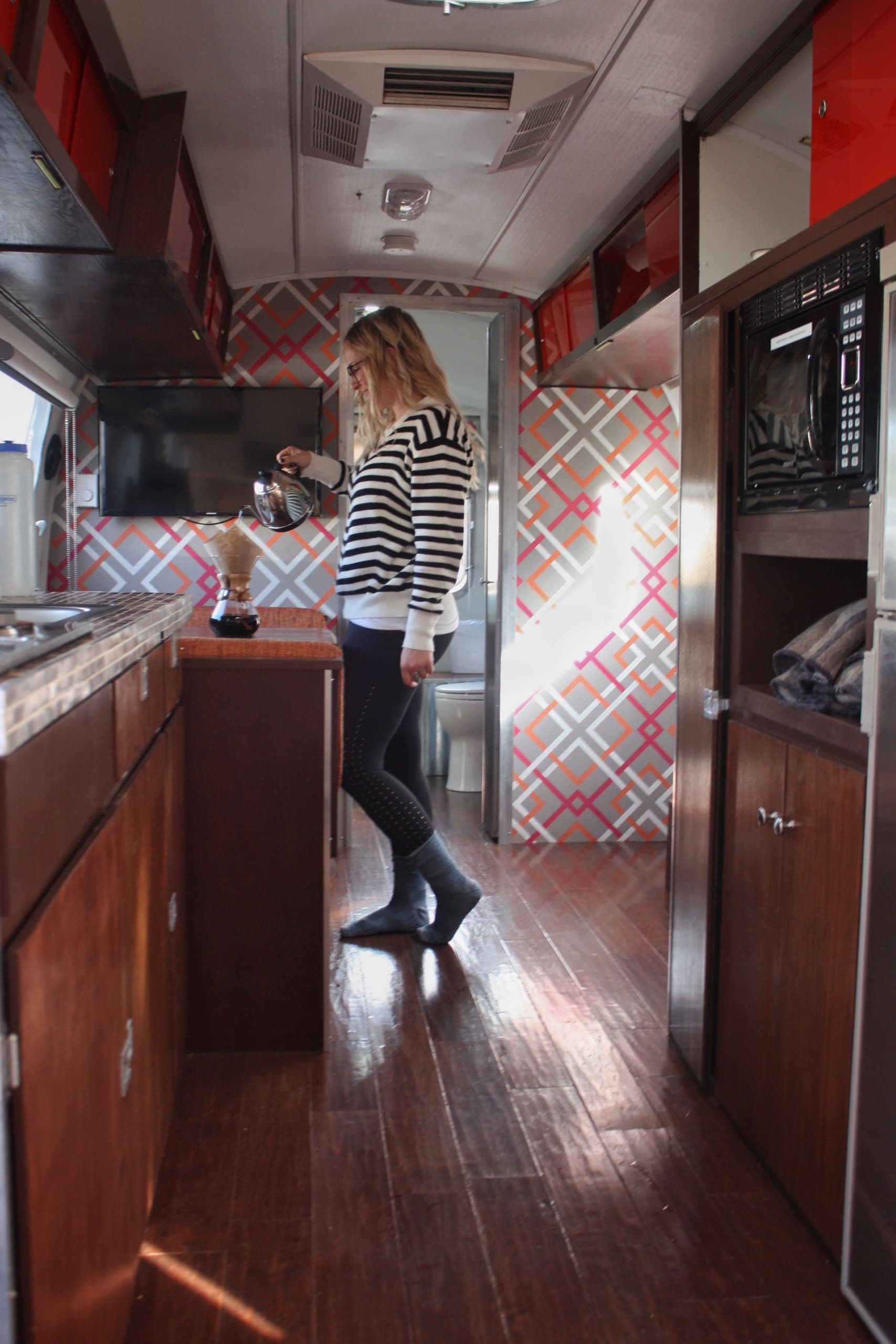 A woman making coffee in ab airstream at Harts Camp