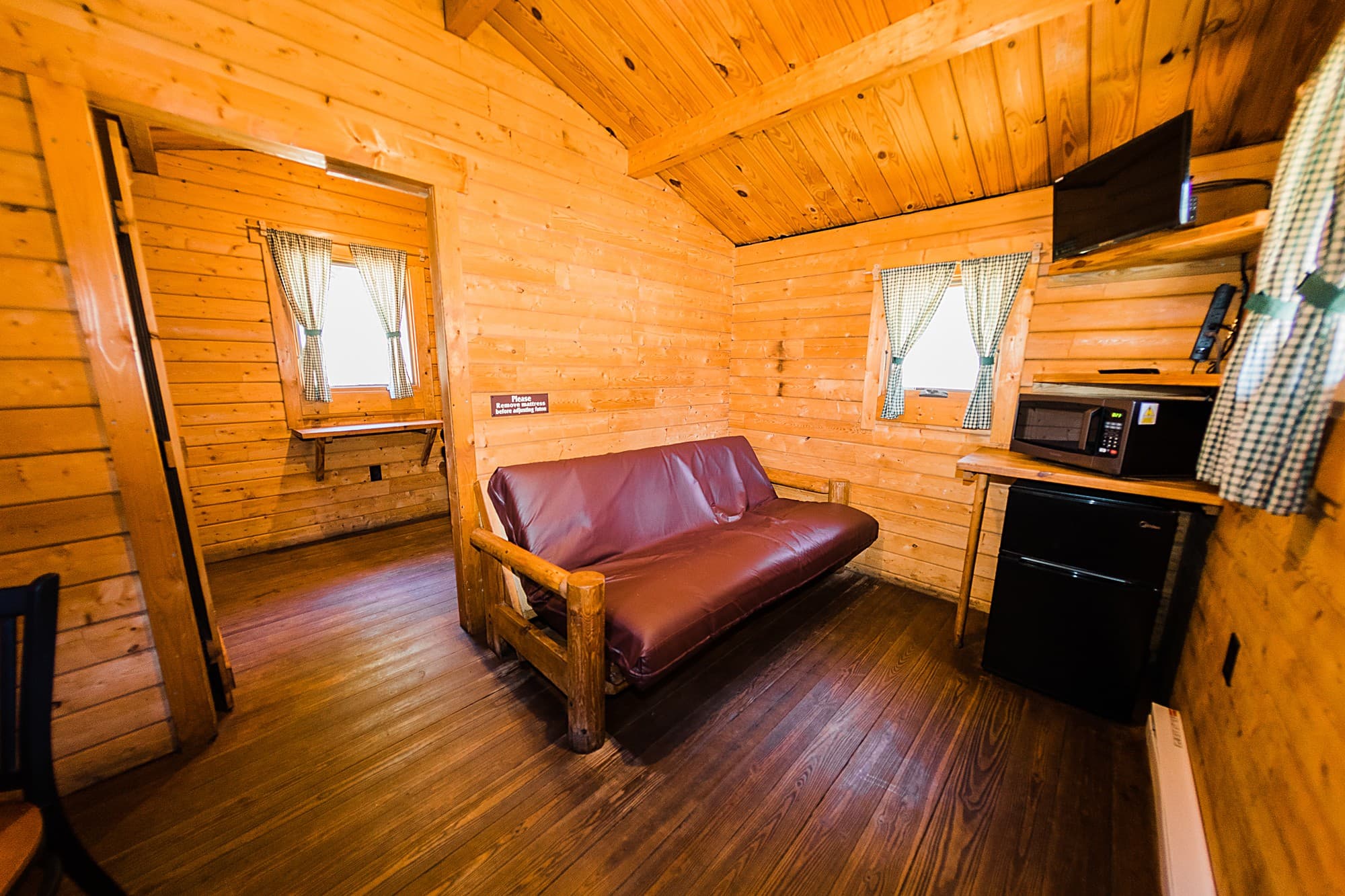 One-bedroom cabin with maroon futon, mini fridge and microwave at The Inn at Hart's Camp near Haystack Rock, Oregon