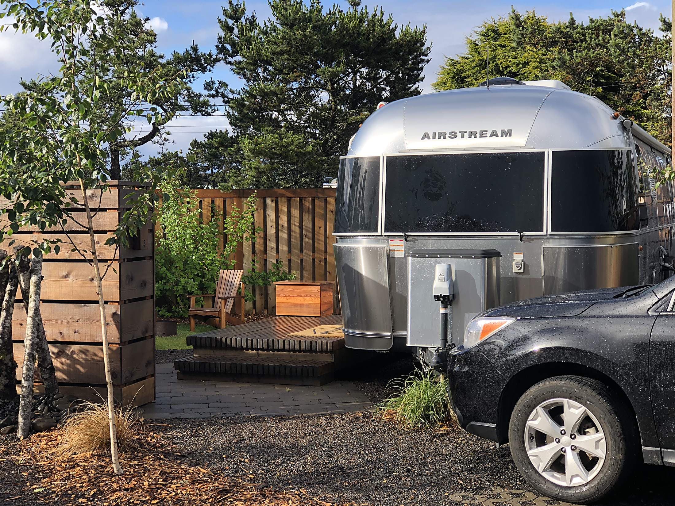 Vintage Airstream trailer with private cedar deck and Adirondack chairs at The Inn at Hart's Camp glamping resort near Cape Kiwanda